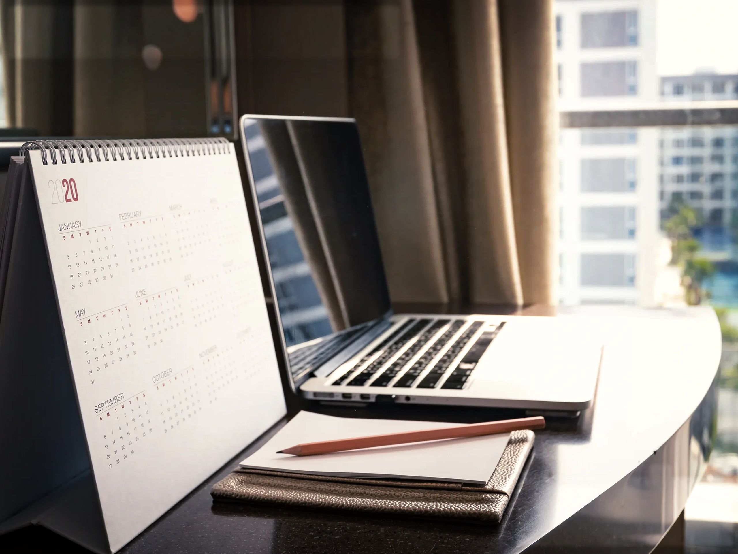 Founder’s workspace with calendar, notebook and laptop, illustrating inbox and schedule efficiency support by a virtual assistant