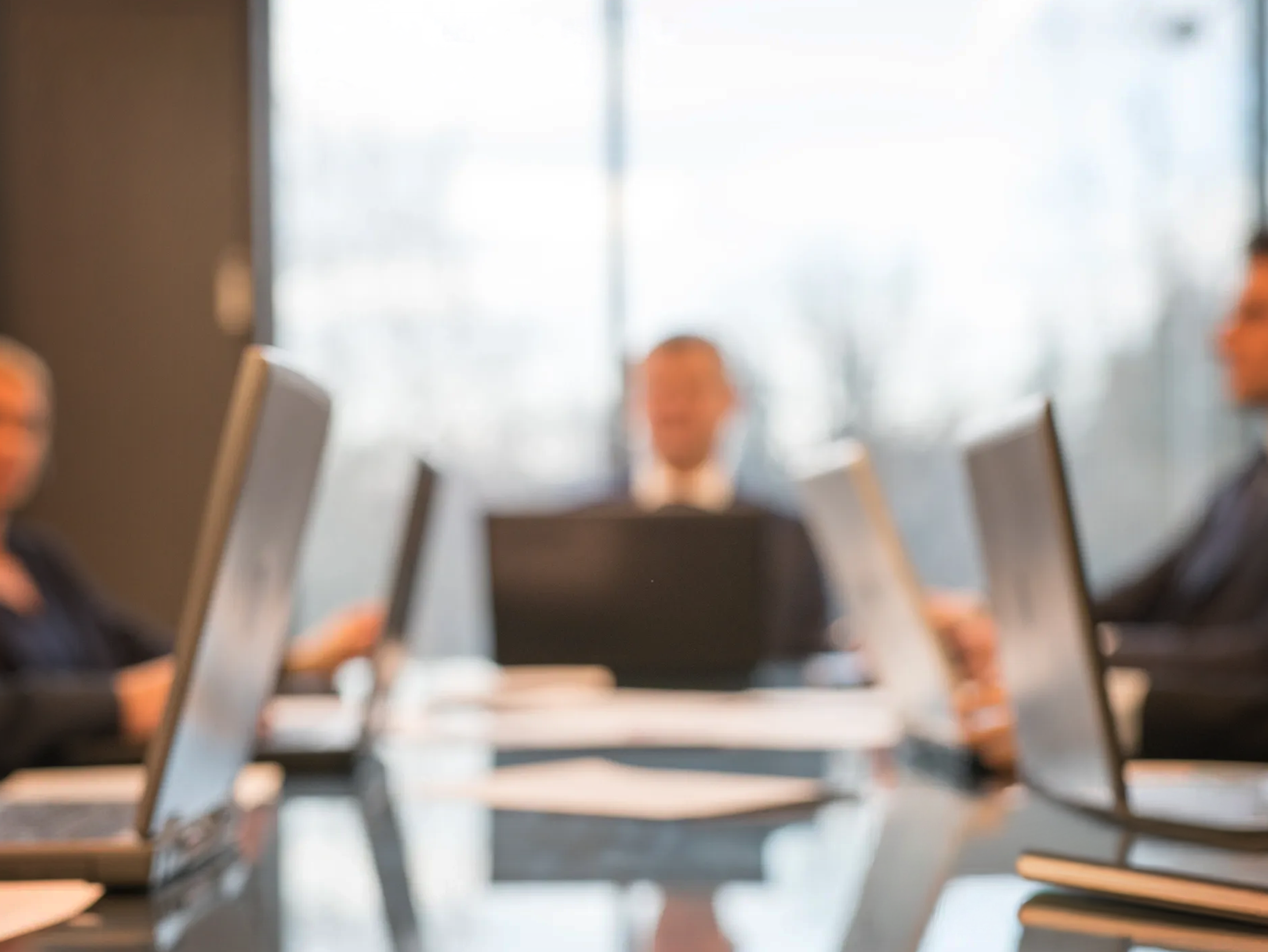 Executive leadership meeting with laptops, illustrating global governance and senior stakeholder coordination support