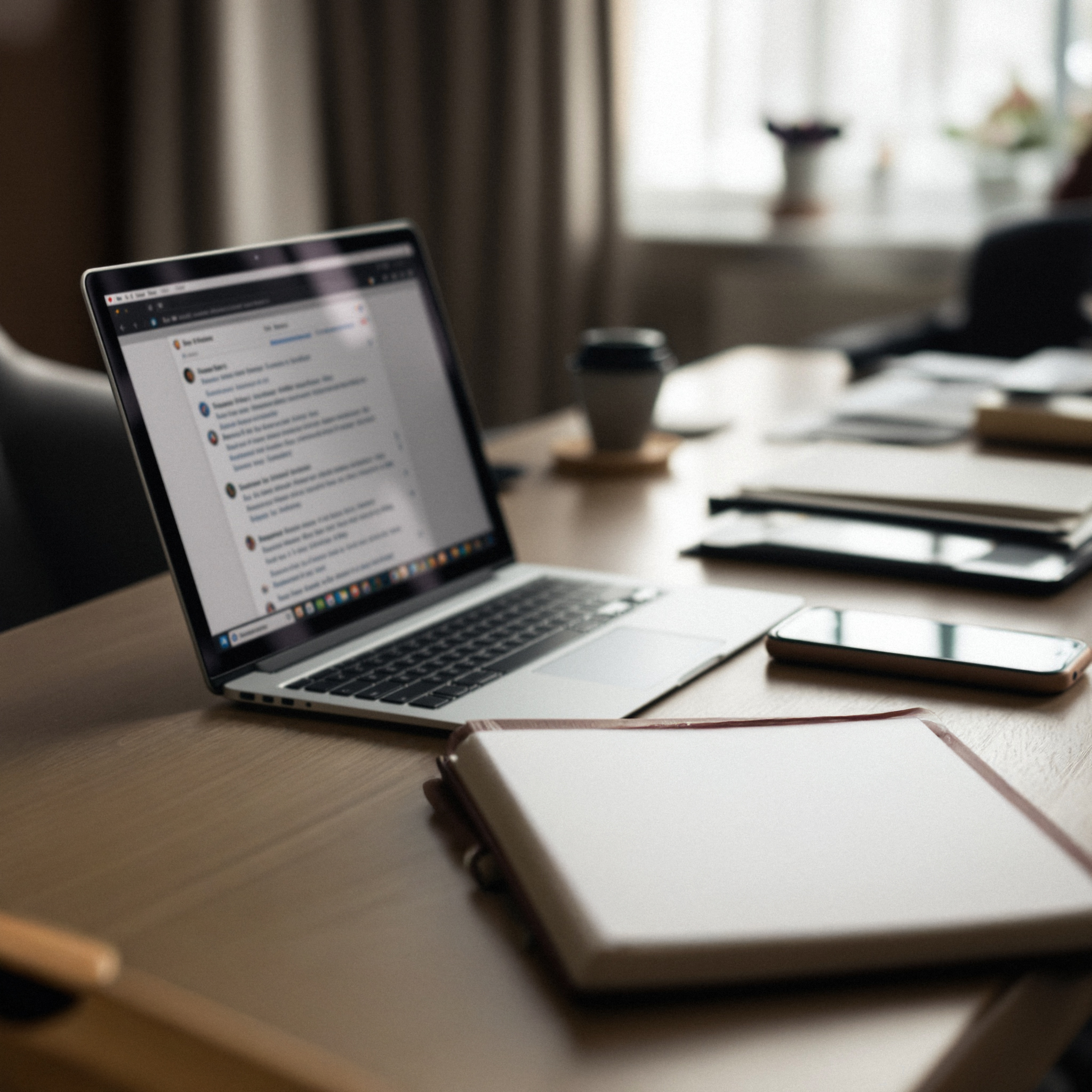 A laptop and notebook on a quiet desk, showing a founder’s inbox and daily work setup